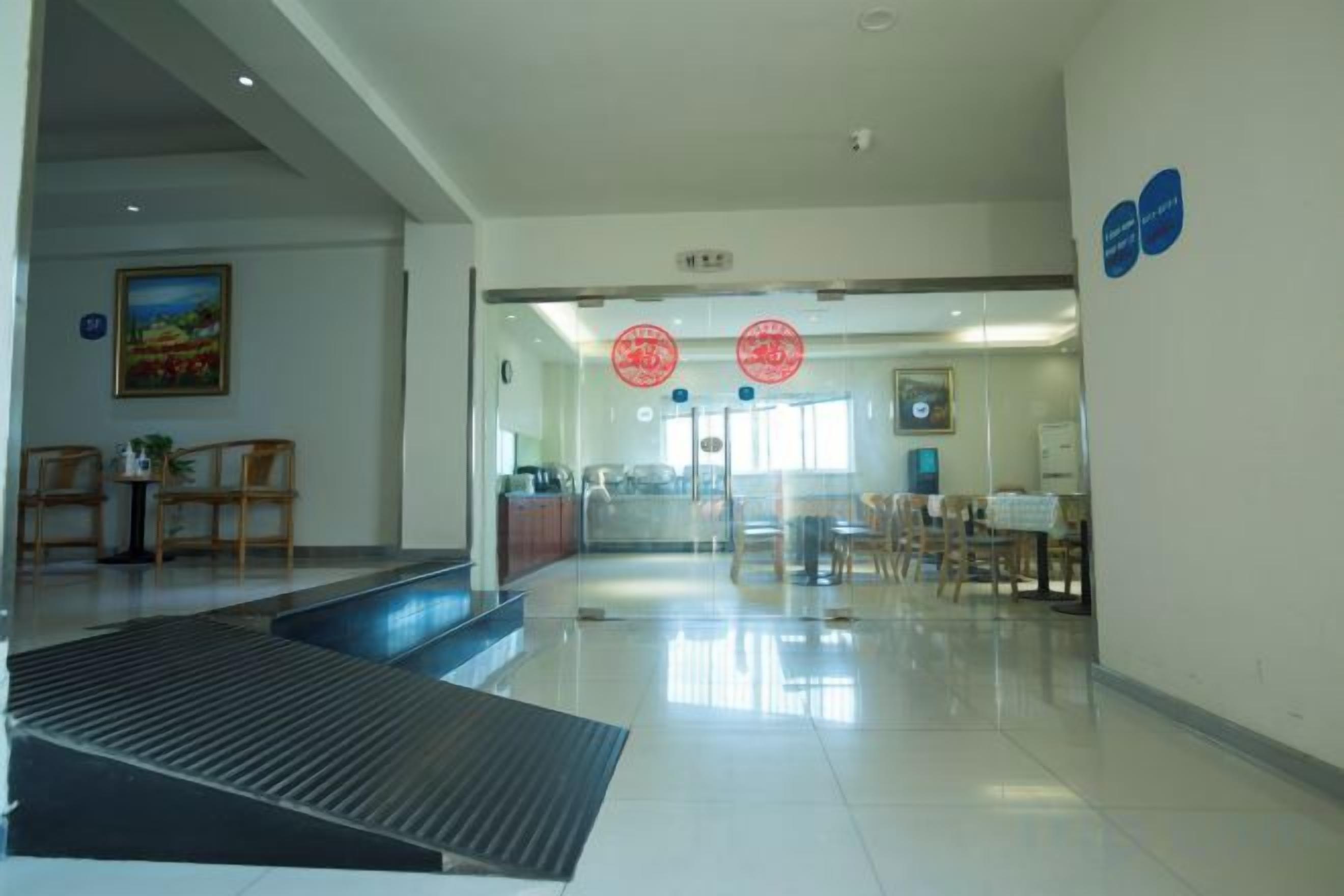 A hotel lobby with a reception desk, seating area, and a staircase leading to upper floors.