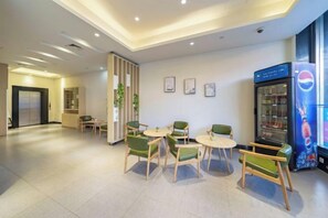 Un hall d’hôtel doté d’espaces aménagés avec des sièges, d’un réfrigérateur et d’un distributeur automatique.