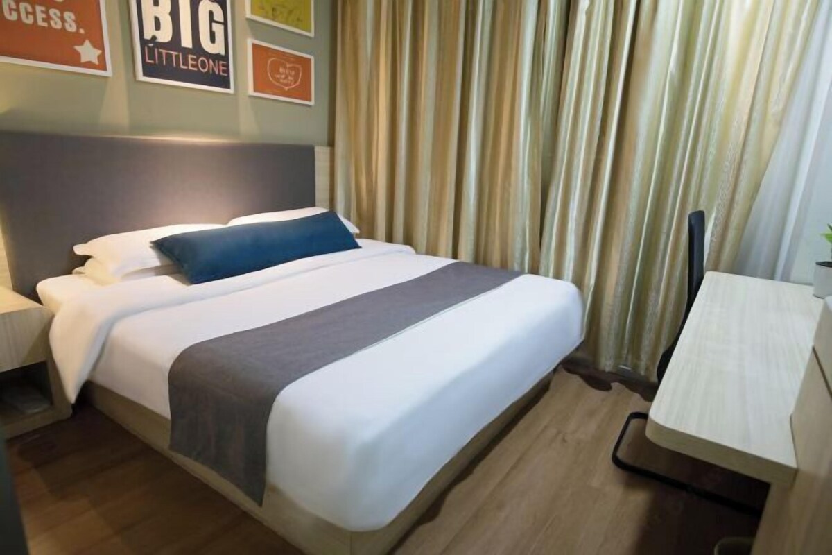 Una camera d'albergo con un letto, un comodino, una scrivania e tende.