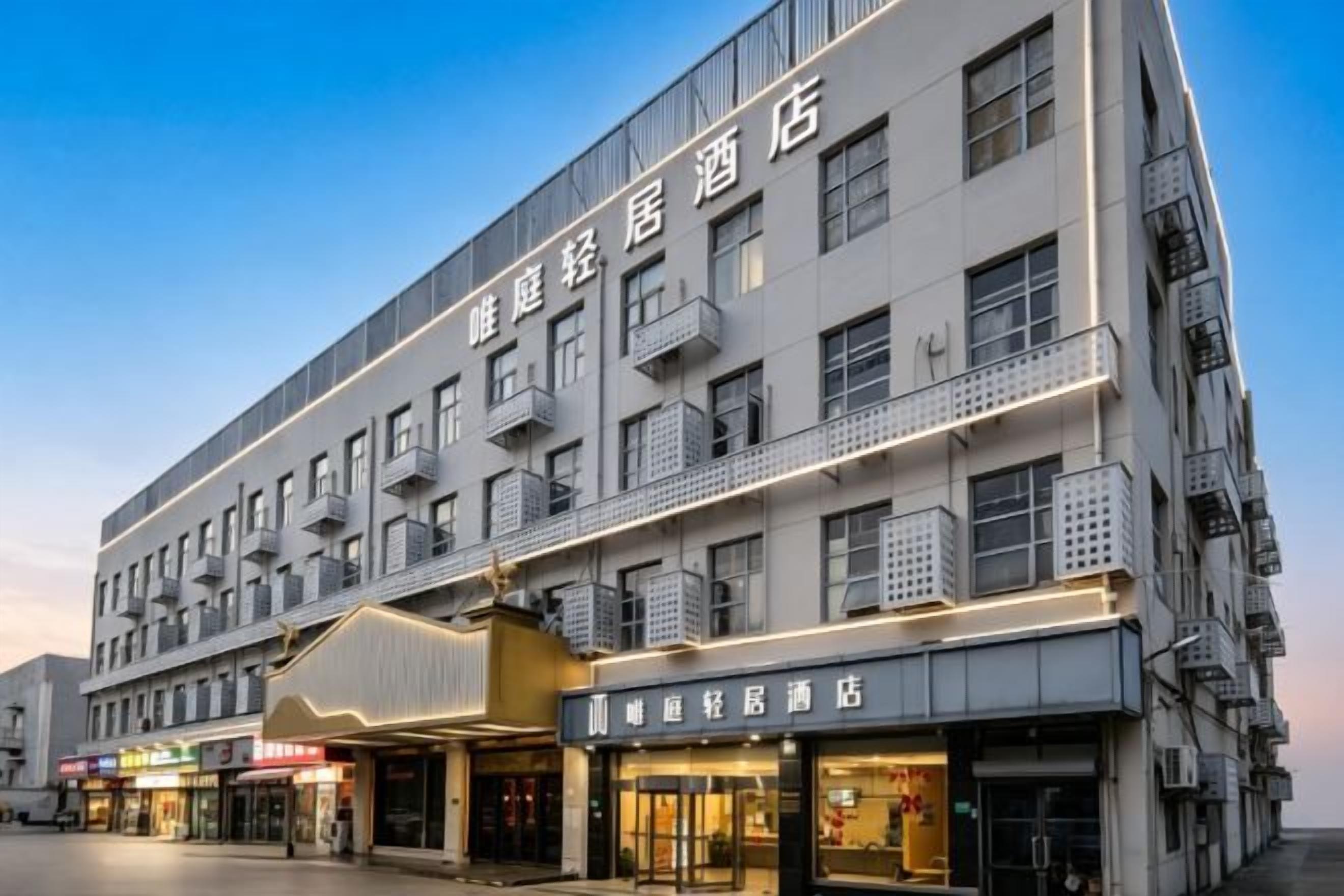 Un hotel de varios pisos con balcones, señalización para un restaurante y una fachada comercial.