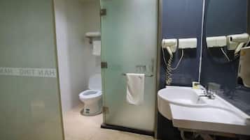 A bathroom with a toilet, a glass door, a sink, and a towel rack.