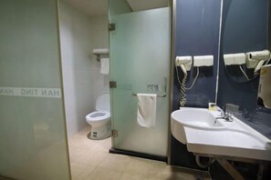 Un bagno con il water, una porta in vetro, un lavandino e un portascopevoli.