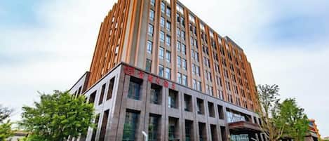 A multi-story building with a modern architectural design, featuring a prominent entrance with glass doors and a flat roof.