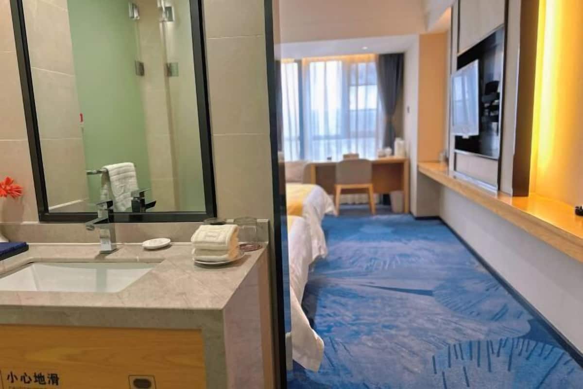 Ein Hotelzimmer mit Bad, Bett, Schreibtisch und Fernseher.