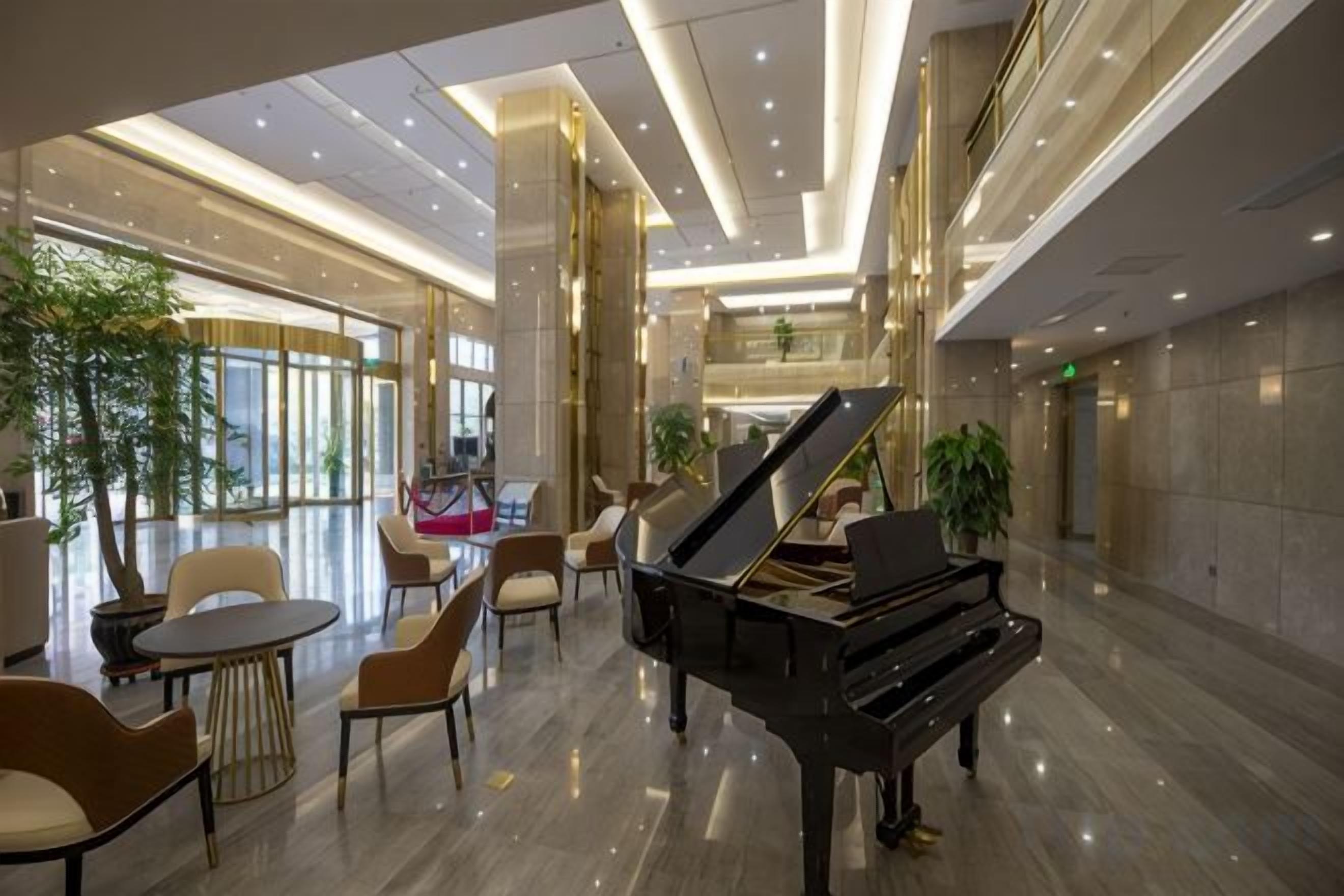 Un hall d’entrée spacieux, agrémenté d’un magnifique piano à queue, de sièges confortables et d’un escalier moderne.