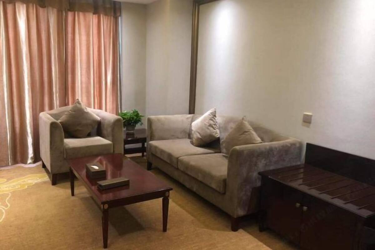 Ein Wohnzimmer mit einer Couch, einem Sessel, einem Couchtisch und einem kleinen Tisch mit einer Pflanze.