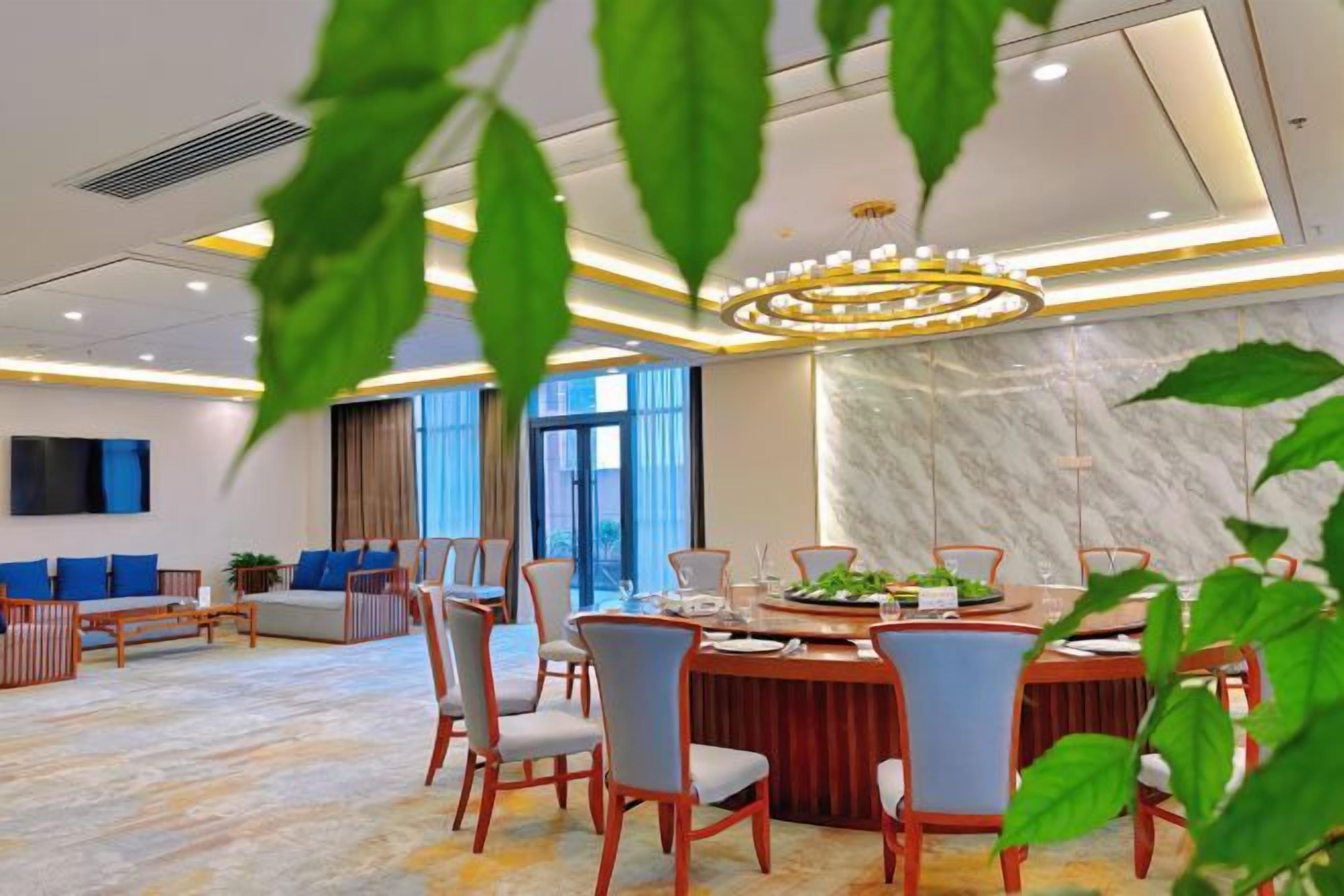 Un comedor moderno en un hotel, con pared de mármol, una mesa redonda y sillas azules.