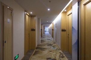 Un pasillo de hotel con puertas de madera, alfombra estampada y un cartel que indica la habitación 410.