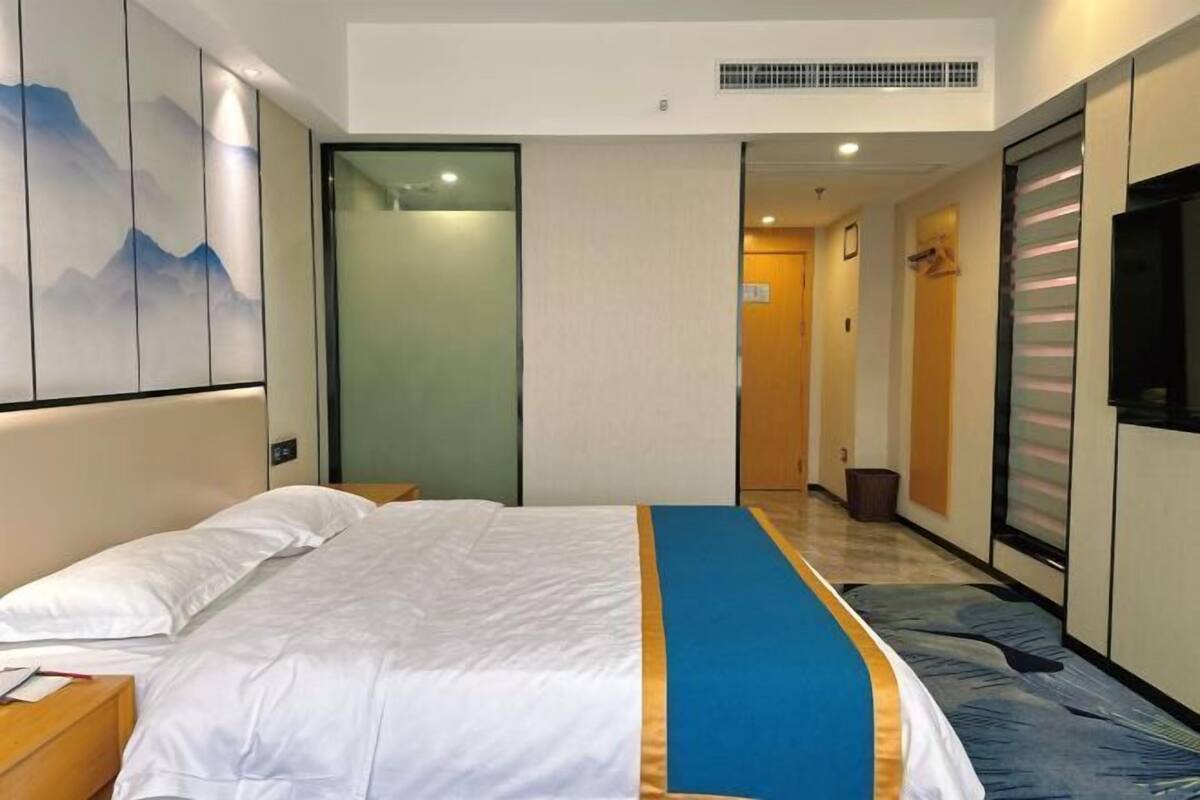 Ein Hotelzimmer mit Bett, Schreibtisch, Stuhl, Kleiderschrank und Fernseher.