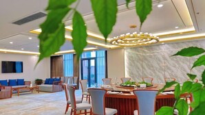 Un comedor de hotel moderno con pared de mármol, una araña y una mesa redonda con sillas.