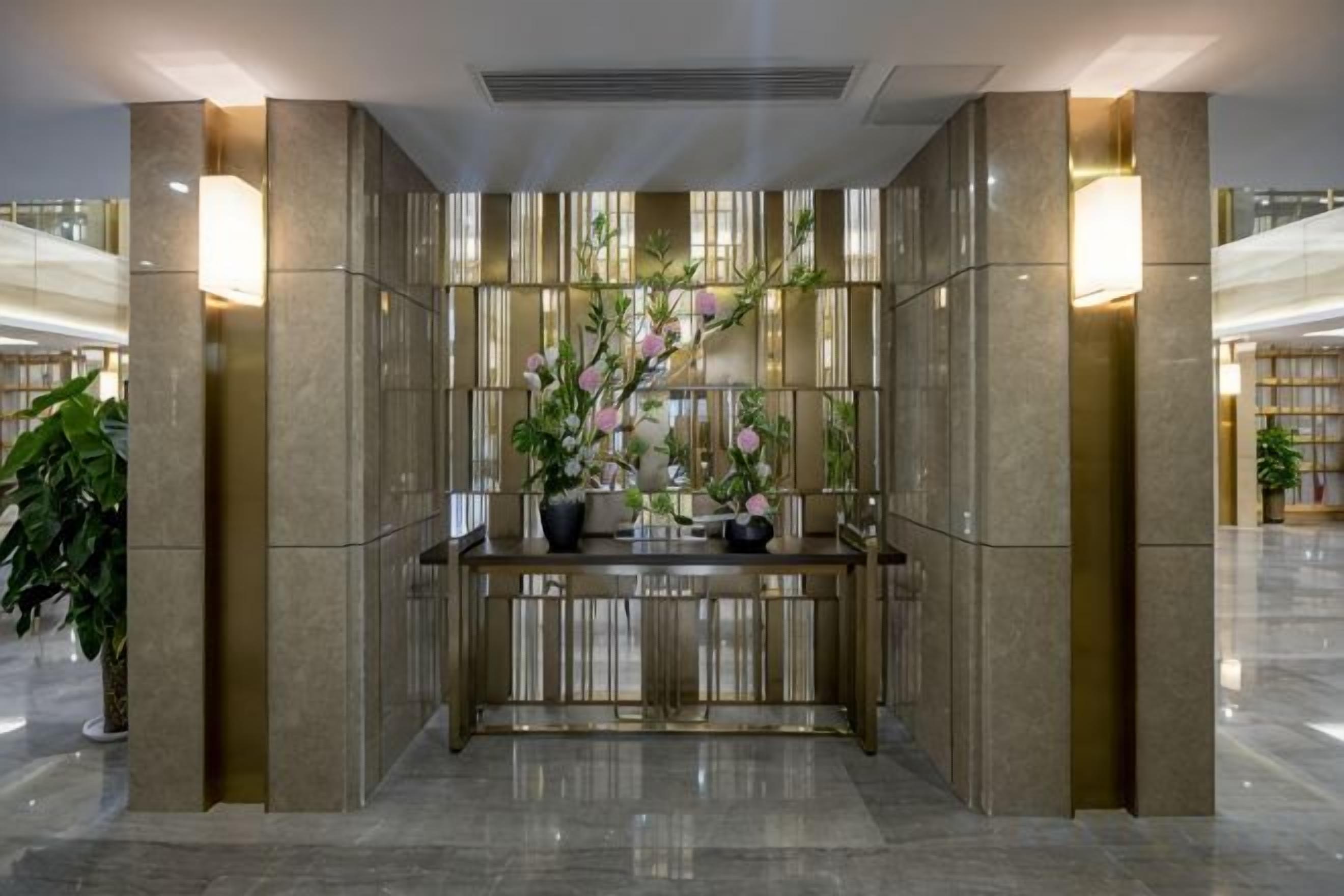 A reception area with a marble reception desk, potted plants, and a view of the lobby.