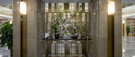 A reception area with a marble reception desk, potted plants, and a view of the lobby.
