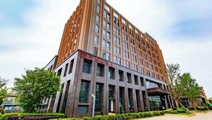 Un edificio moderno de varios pisos con una entrada destacada y un amplio frente de vidrio.