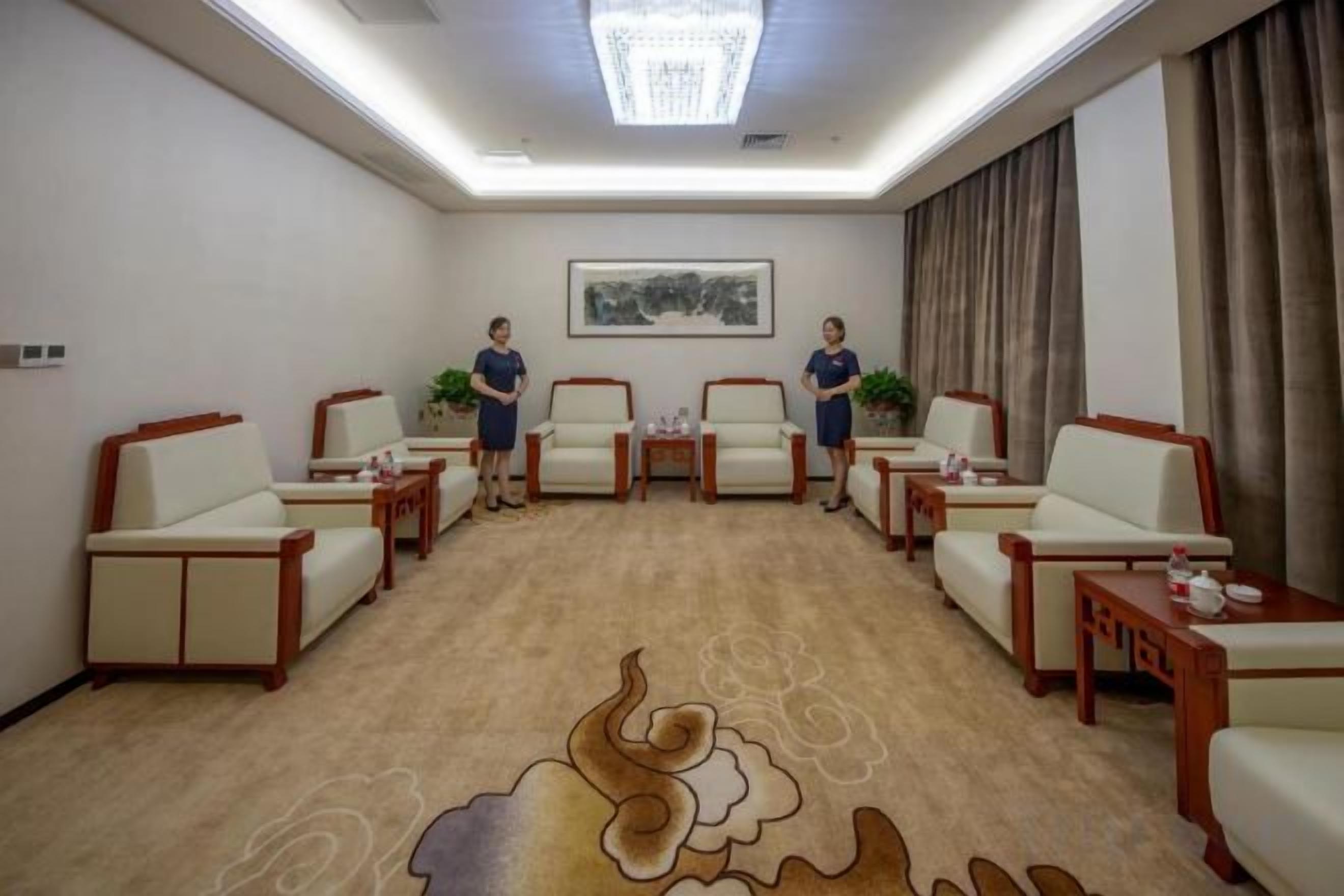 A conference room with a carpeted floor, a chandelier, and a painting on the wall.