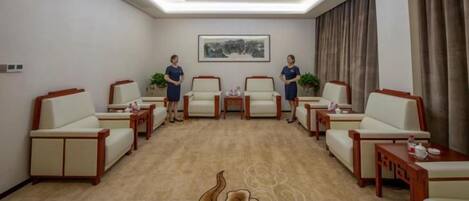 A conference room with a carpeted floor, a chandelier, and a painting on the wall.