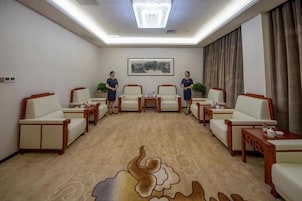 Un salón de conferencias con piso alfombrado, una araña de cristal y un cuadro en la pared.