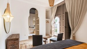 A bedroom with a bed, a desk, chairs, a hanging light fixture, and a wardrobe. - Luxurious 6-bedroom private riad with pool and AC in Marrakesh - Aubiane 88 (Marrakech)