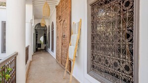 A corridor with a wooden door, a window with ornate metal bars, and a hanging light fixture. - Luxurious 6-bedroom private riad with pool and AC in Marrakesh - Aubiane 88 (Marrakech)