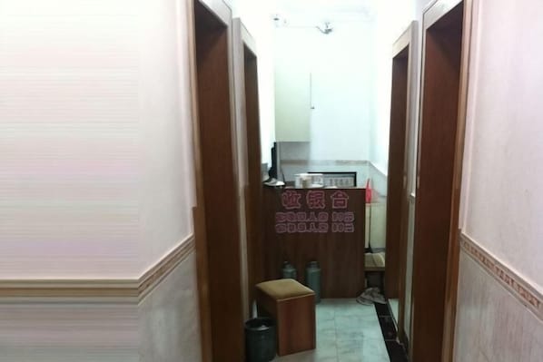 A narrow hallway with wooden doors, a small stool, and a trash bin. - Jincheng Hostel (Shanghai)