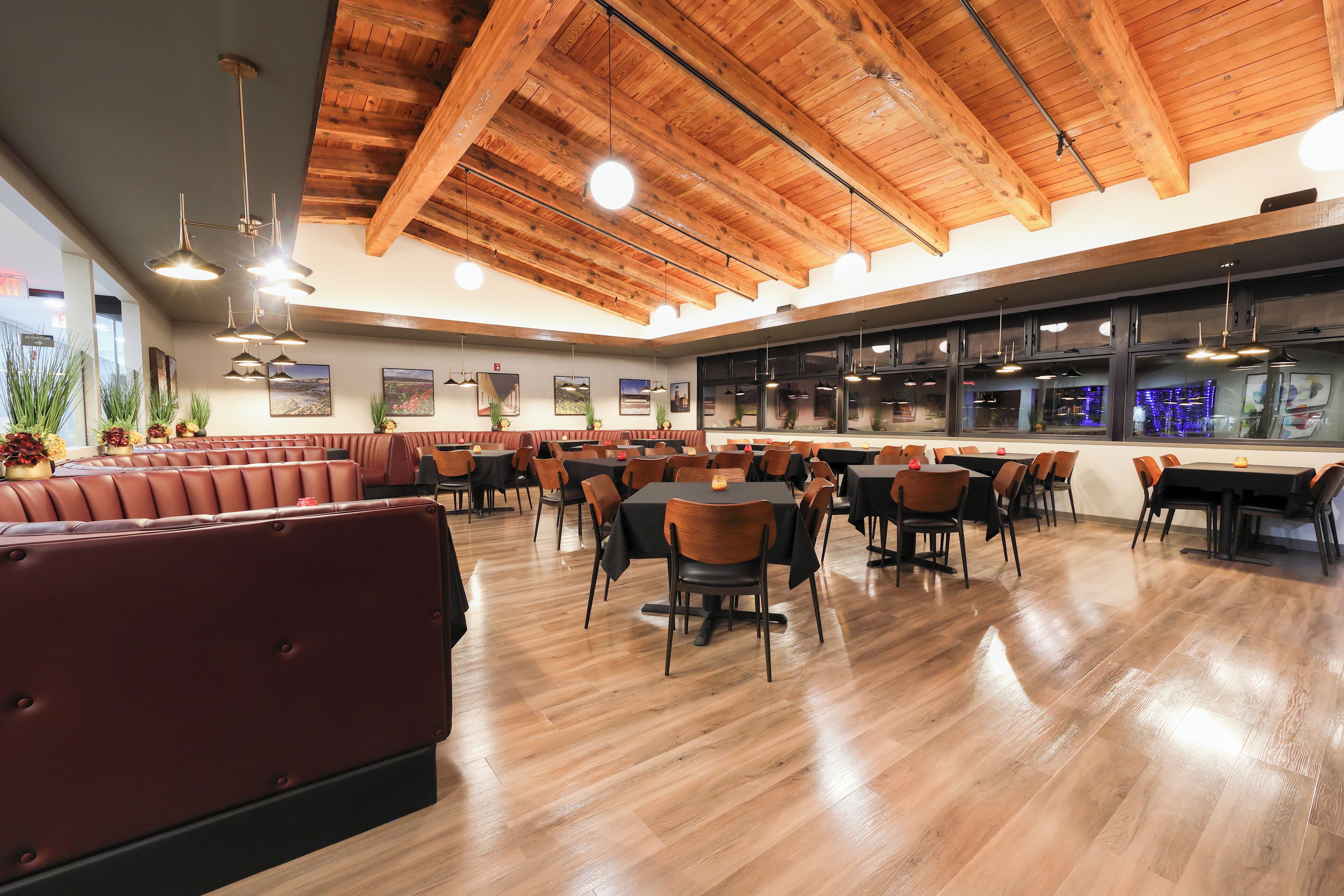 Un restaurante espacioso con techos de madera, varias mesas y sillas para comer, y una zona de bar.