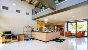 A modern hotel lobby with a reception desk, seating area, and a stone wall. - Village Inn  (Lompoc)