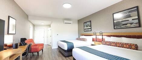 Habitación de hotel con dos camas, un escritorio y una silla.