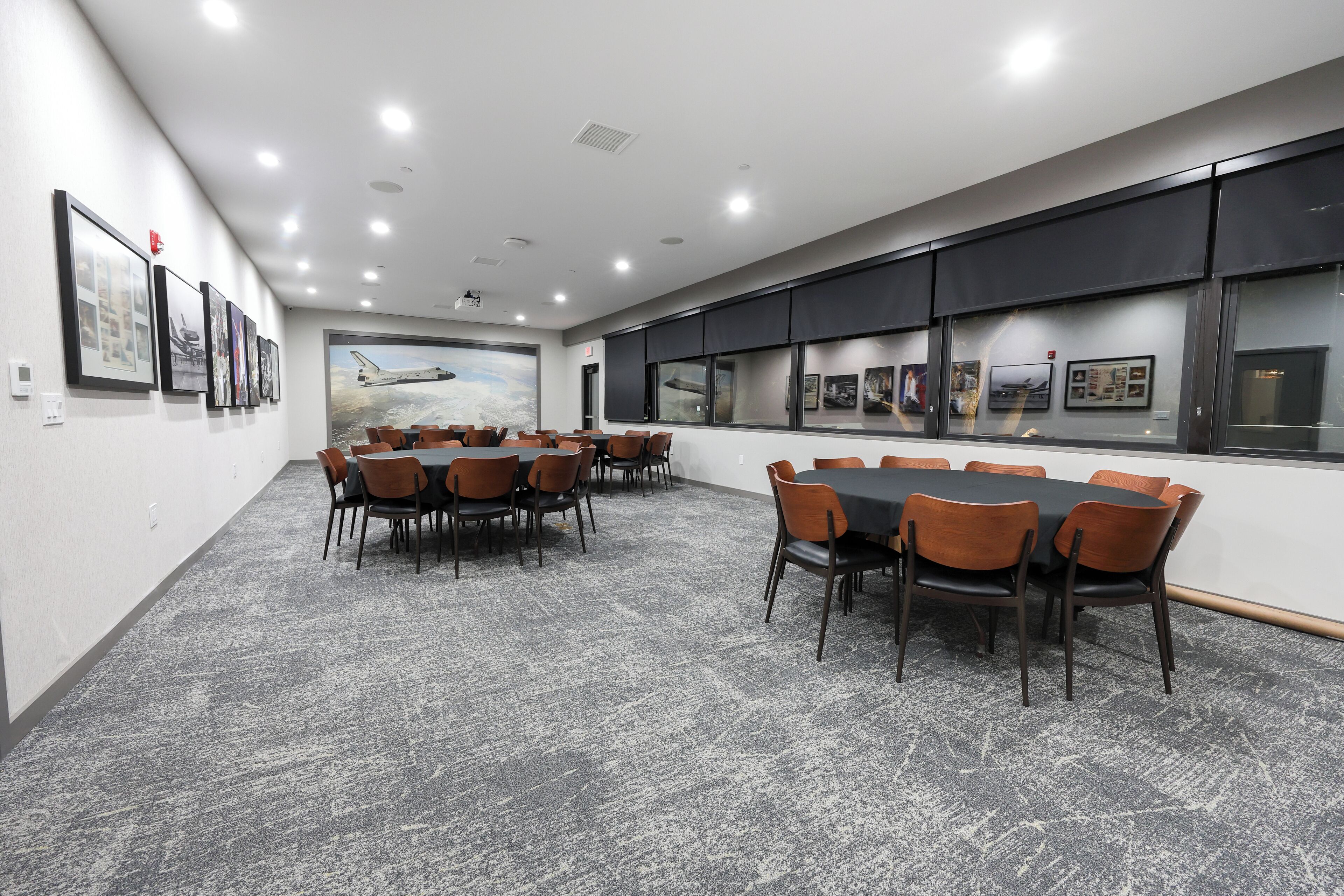 Una sala conferenze con un grande tavolo e sedie, uno schermo per proiettore e quadri appesi alle pareti.