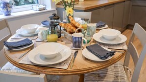 A breakfast table set with plates, bowls, a coffee pot, and a basket of croissants. - Bradley's Barn (Colchester)