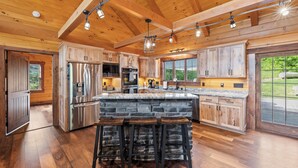 A spacious kitchen with wooden cabinets, a large island with stools, and a stone countertop.