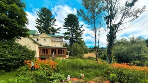 Une maison entourée d’un jardin où poussent différentes plantes et fleurs.