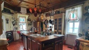 A rustic kitchen with a large island, wooden cabinets, and a fireplace. - Vintage Inspiration & Creative Tools in a Victorian Manor (Namur)