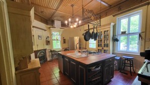 Une cuisine spacieuse dotée d’un grand îlot central, de meubles en bois et d’un porte-ustensiles suspendu.
