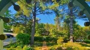 A pathway leading through a garden with trees and shrubs, a white fence, and a parked car in the background. - The Cinema Room with Spa - Le Salon des Inconnus (Namur)