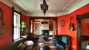 A cozy living room with a fireplace, bookshelves, a green sofa, and a black armchair. - The Cinema Room with Spa - Le Salon des Inconnus (Namur)