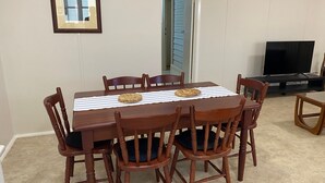Un coin repas avec une table et des chaises en bois, une nappe à rayures et des sets de table en fibres tressées.