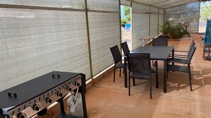 Eine Terrasse im Freien mit Grill, Tischen und Stühlen.