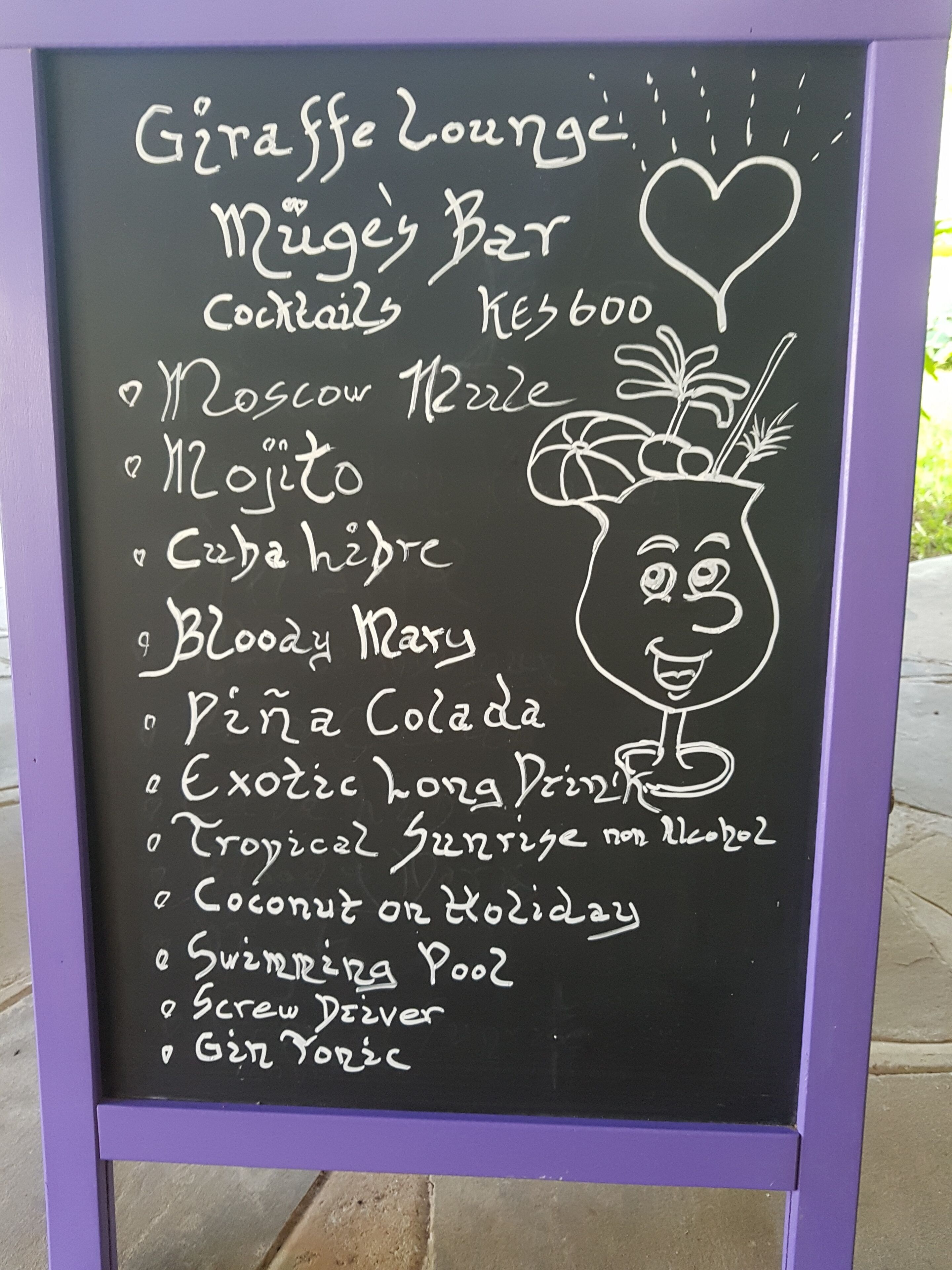 A chalkboard menu listing cocktails and prices at Giraffe Lounge.