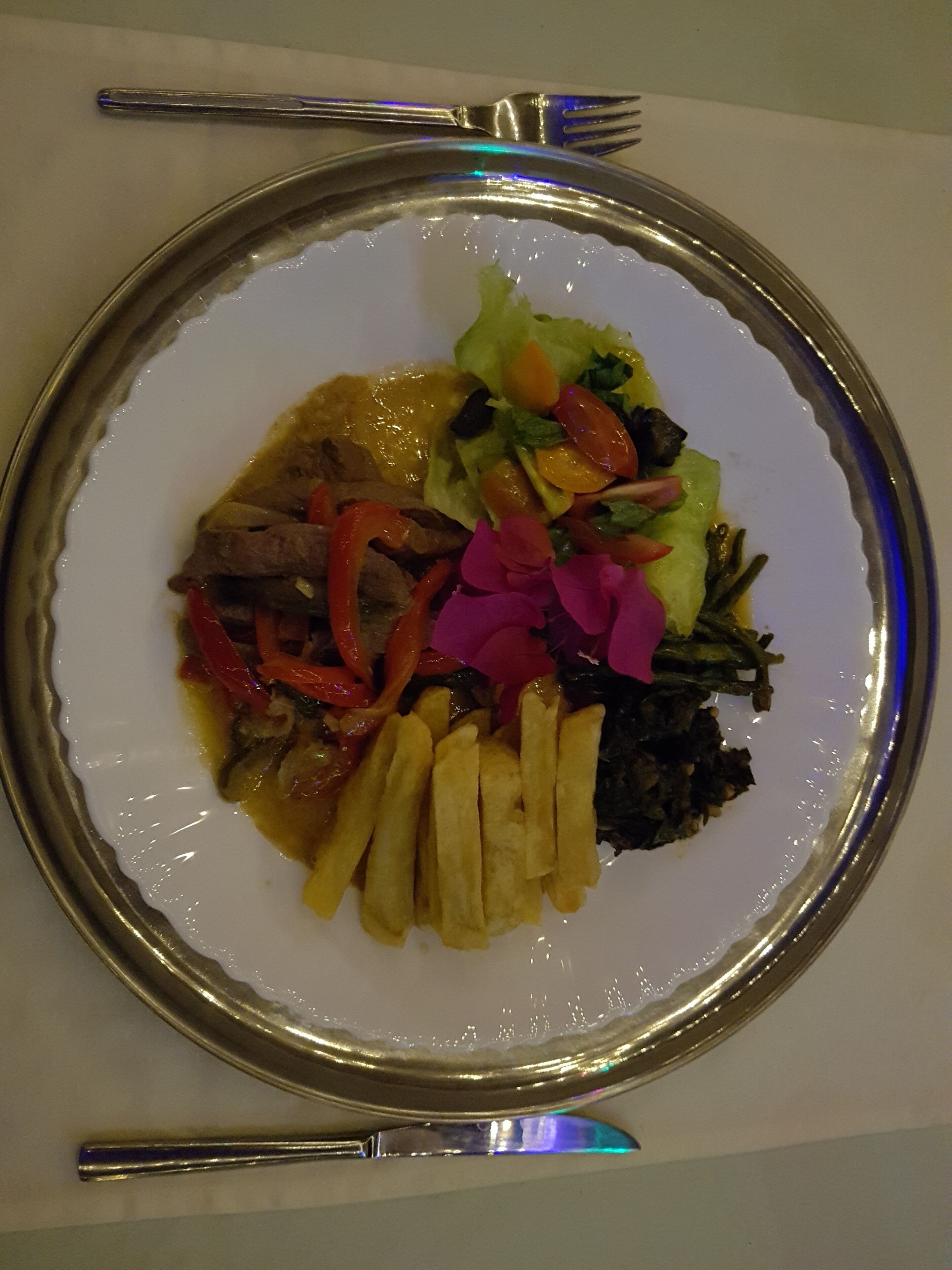 Un plat de menjar amb diferents ingredients, com ara carn, verdures i patates fregides.