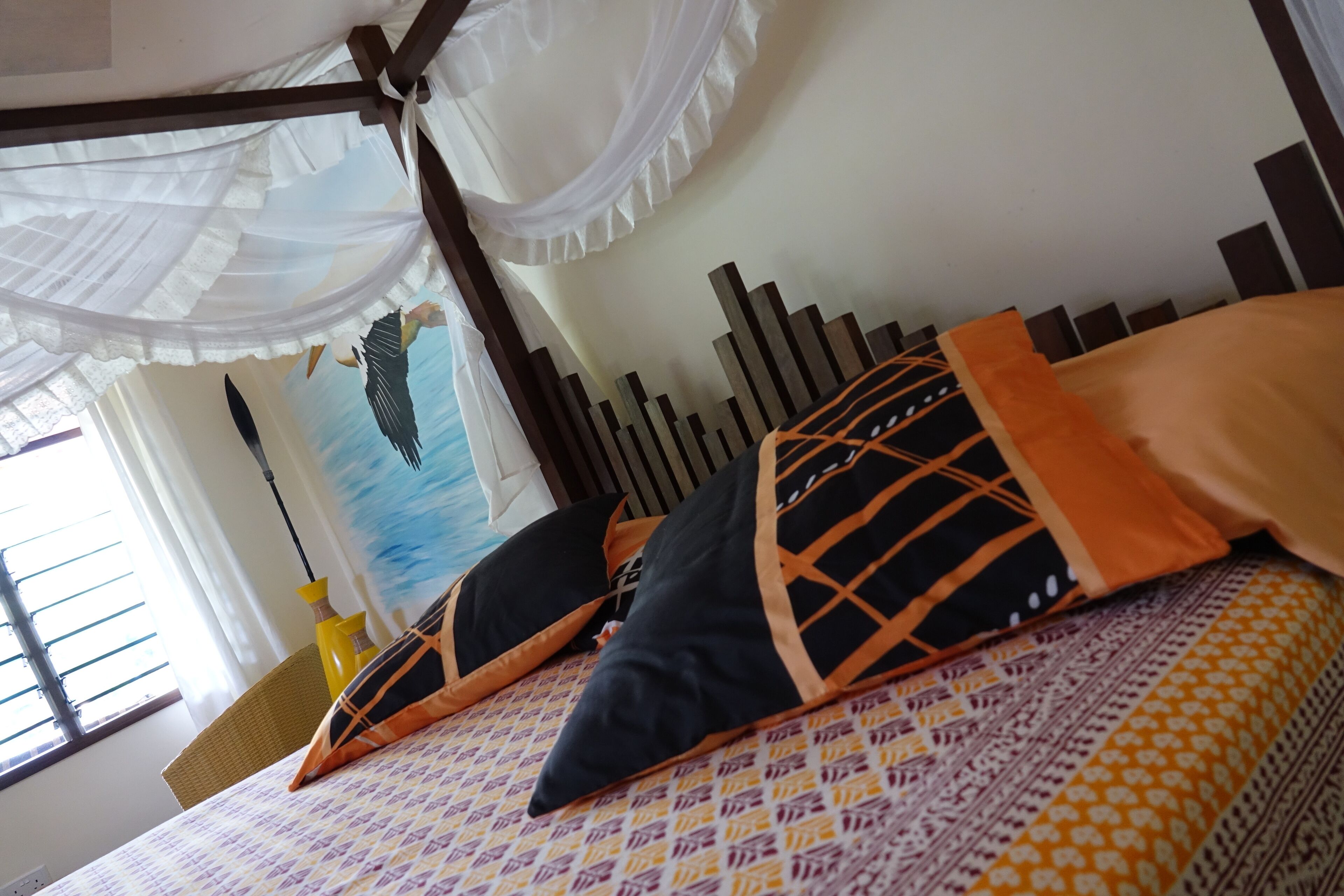 A bed with patterned bedding, a canopy, and decorative pillows.