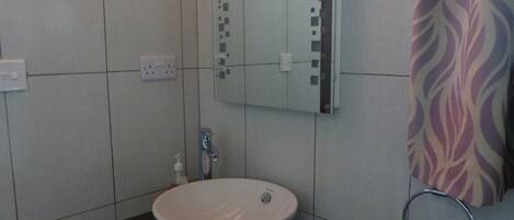 Un baño con un lavabo blanco, un espejo y un perchero para toallas.