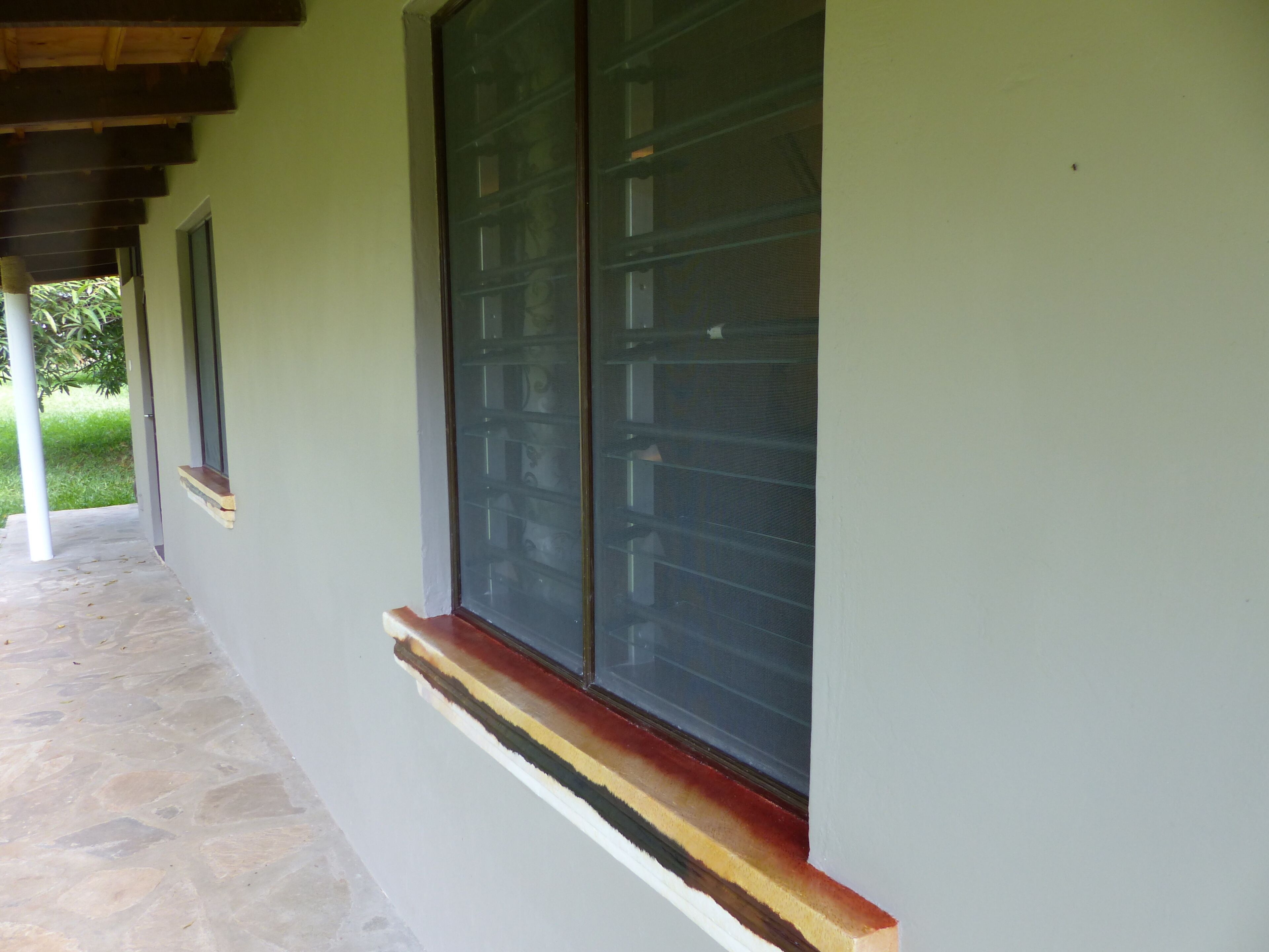 Fachada de edificio con un gran ventanal, entrada empedrada en piedra y estructura de techo de madera.