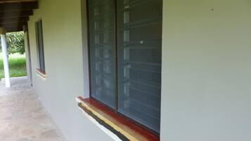 Fachada de edificio con un gran ventanal, entrada empedrada en piedra y estructura de techo de madera.