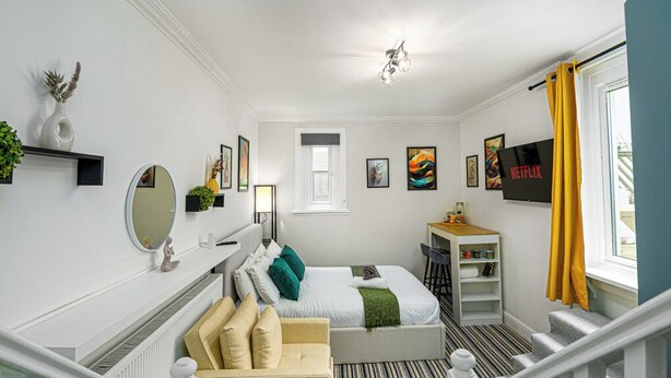 Une chambre d’hôtel moderne équipée d’un lit, d’un bureau, d’une chaise, d’une télévision et d’un escalier.