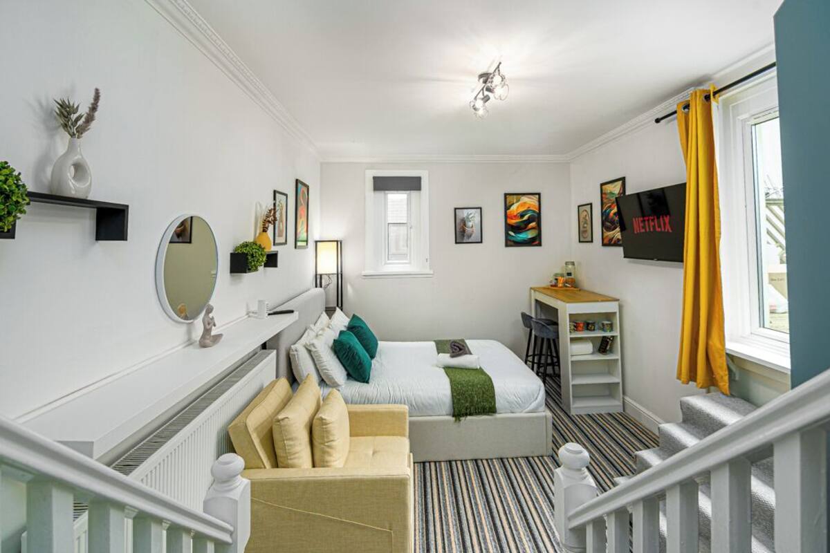 Una habitación de hotel moderna con una cama, un escritorio, una silla, un televisor y una escalera.