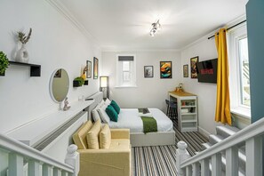 A modern hotel room with a bed, a desk, a chair, a TV, and a staircase. - Highbury & Islington Hub (London)