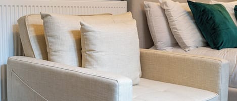 Un fauteuil beige avec un coussin, placé devant un radiateur blanc.