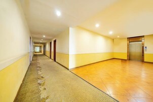 A hotel corridor with carpeted flooring, doors, and an elevator.