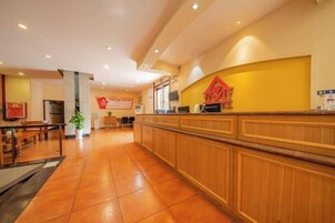 Vestíbulo de hotel con mostrador de recepción, zona de estar y una planta.