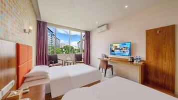 A hotel room with two beds, a desk, a chair, a TV, and a window with a city view.