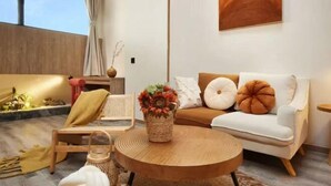 Un salon moderne avec un canapé, une table basse ronde en bois et un vase décoratif.